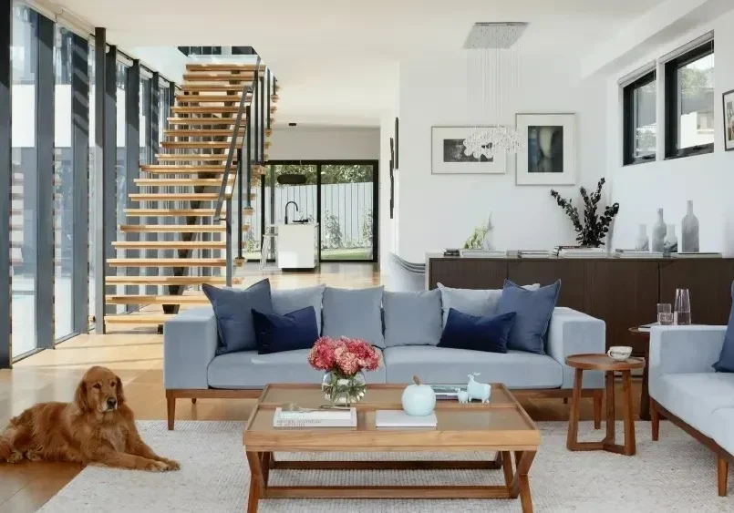 A living room with stairs and a dog sitting on the floor