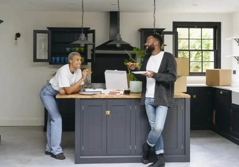 Two people standing in a kitchen with laptops.